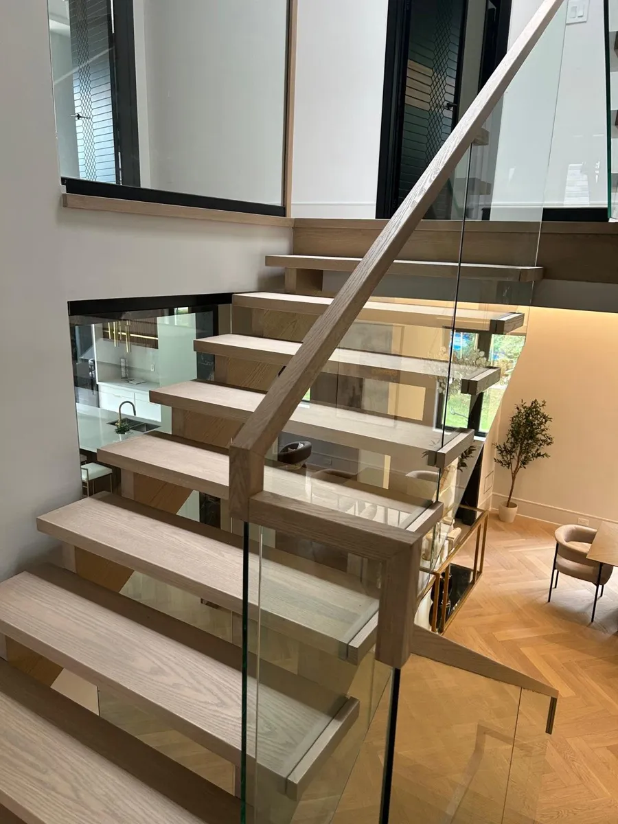 Open-riser light oak staircase with a glass railing
