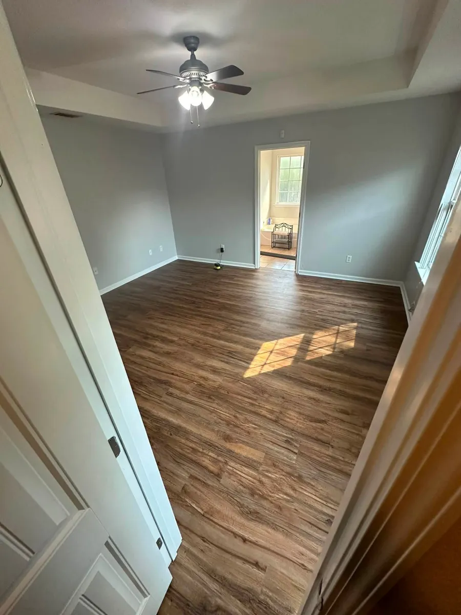 Brown wood-look plank flooring in a finished bedroom with sunlight across the floor